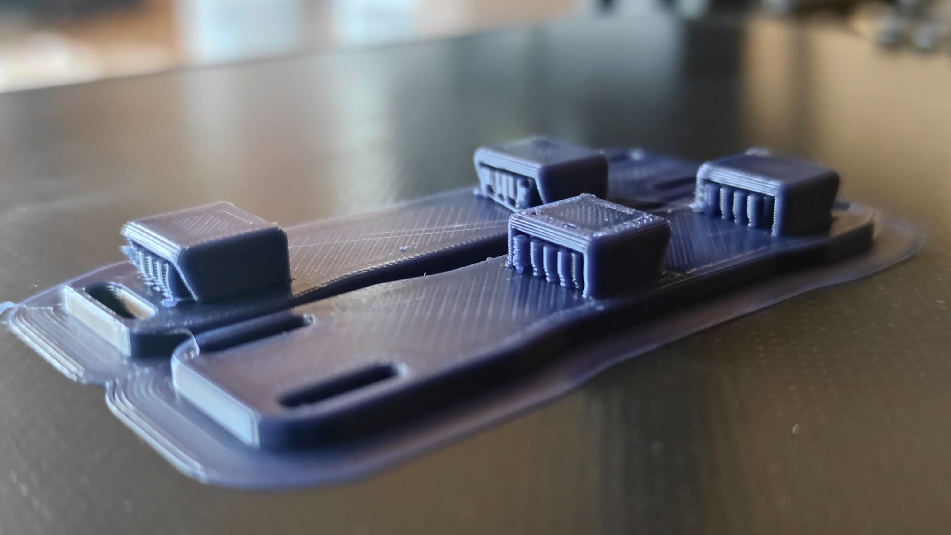 Two 3D printed objects still attached to the 3D print bed after it has finished printing.